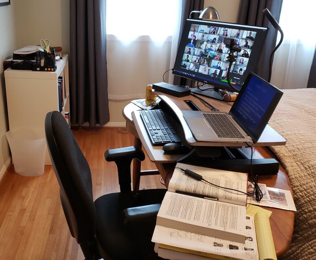 Home office desktop with laptop, monito, and open book