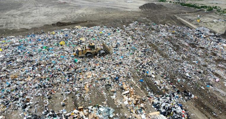 Aerial view of waste and garbage being flattened by heavy machinery at a landfill