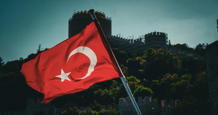 The Turkish flag flapping in the wind with an old building in the background